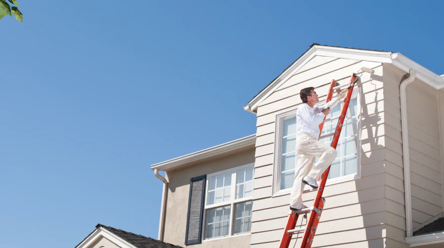 worker painting house exterior